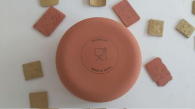 Branded cup Inverted clay cup with logo at the bottom lying among small clay tablets.