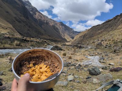 A photo of beans with fritos and vegan cheese